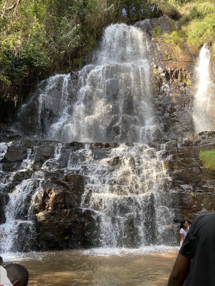 The cascading Karera Waterfall in Burundi — multi-tiered white water over dark rock, framed by lush green foliage